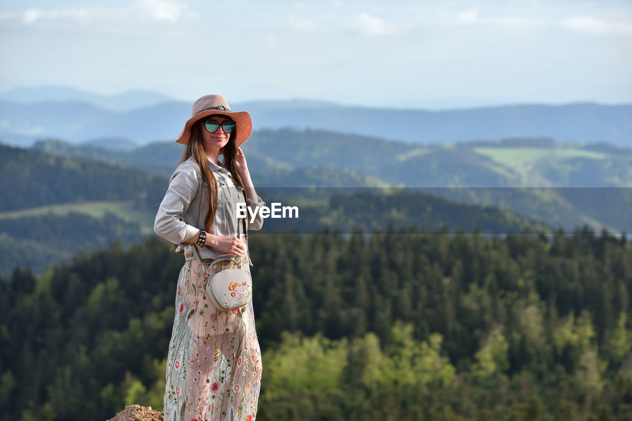 Woman wearing hat and sunglasses while standing against mountain