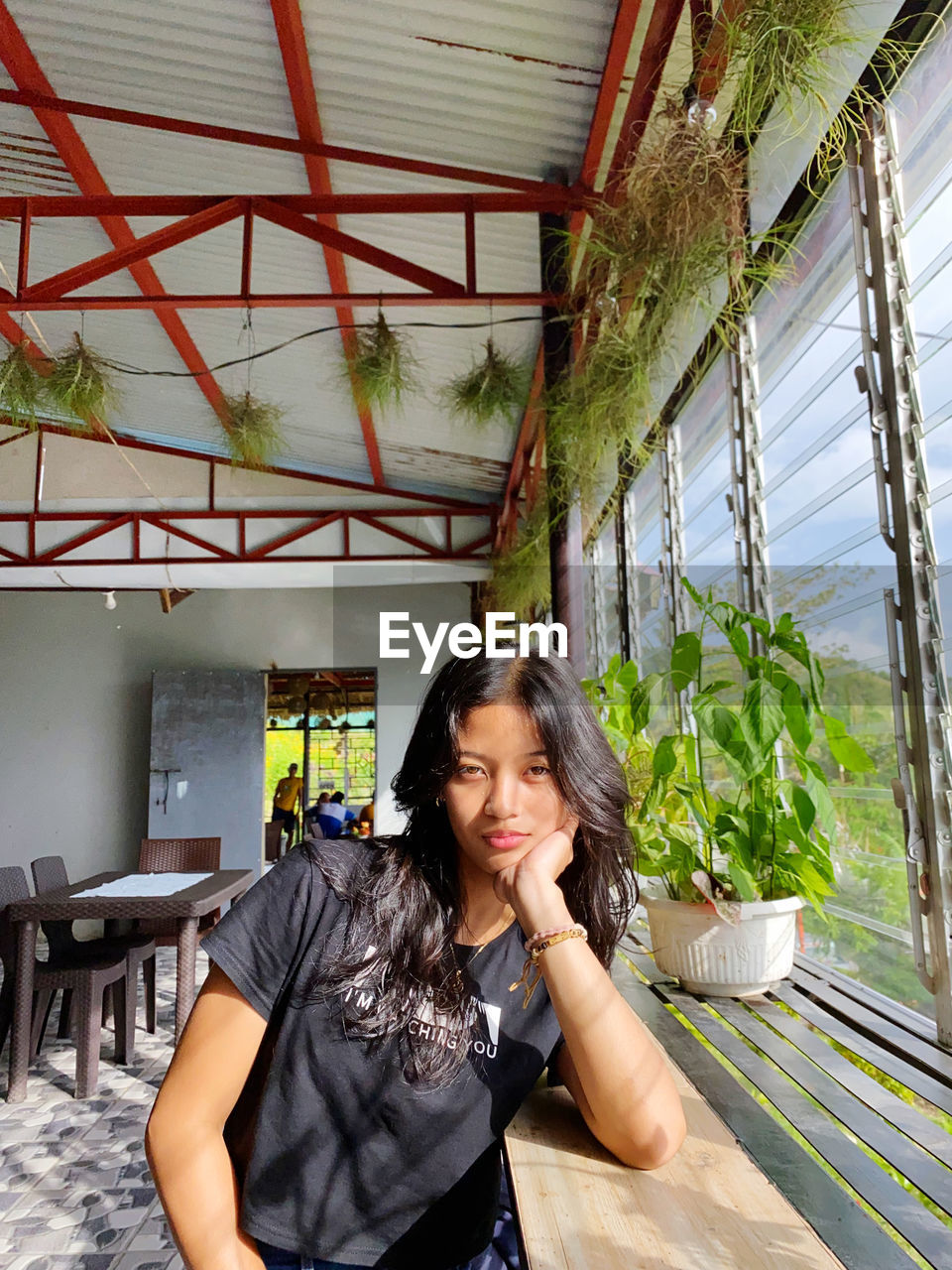 portrait of young woman looking away while standing in greenhouse