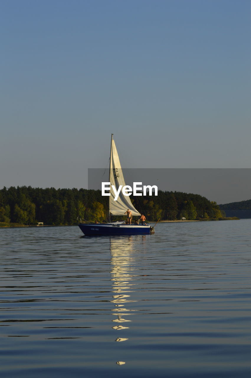 SAILBOAT SAILING ON LAKE AGAINST SKY