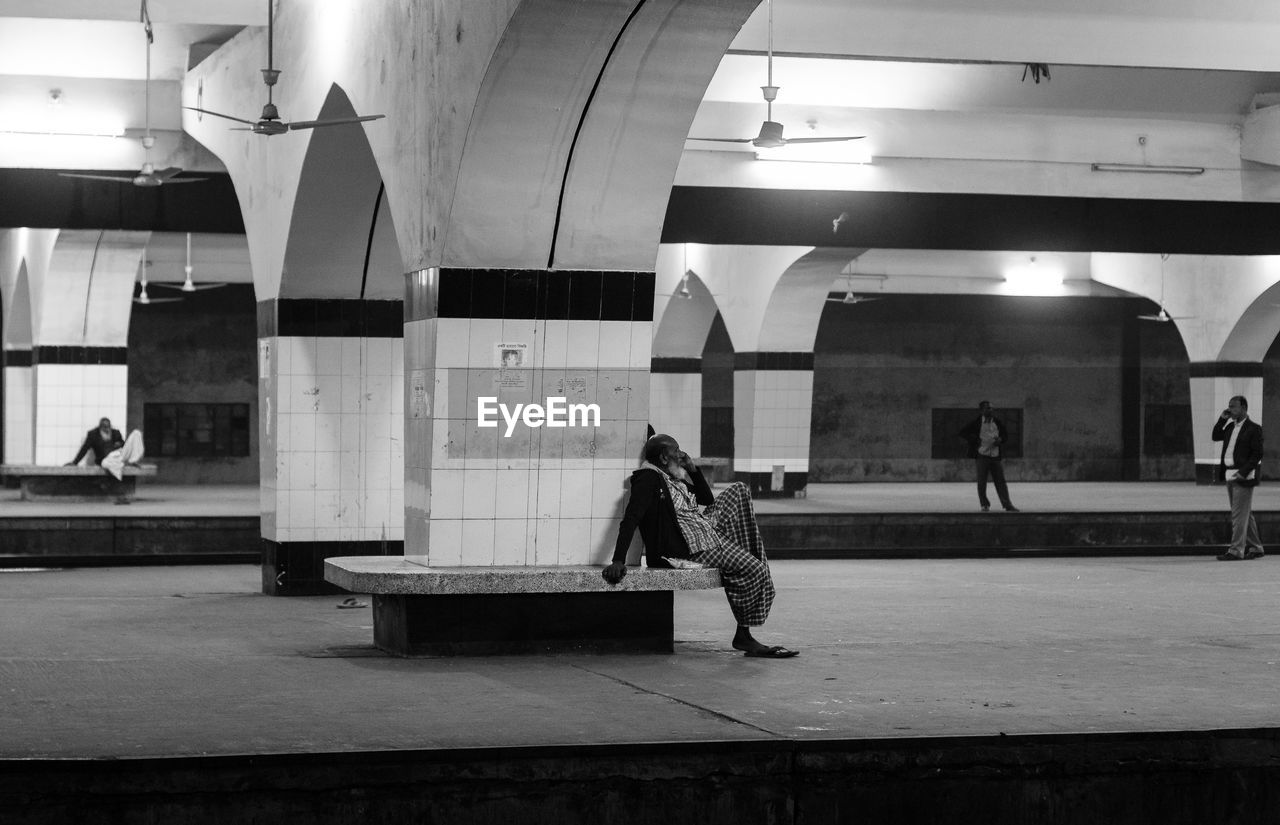 REAR VIEW OF WOMAN SITTING IN ILLUMINATED UNDERGROUND