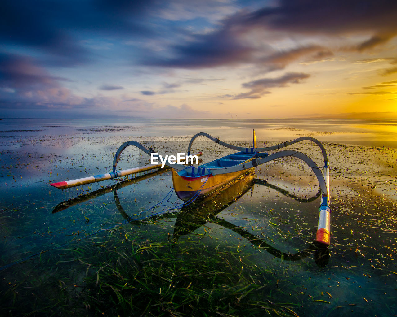 Fishing boat on beach against sky during sunset
