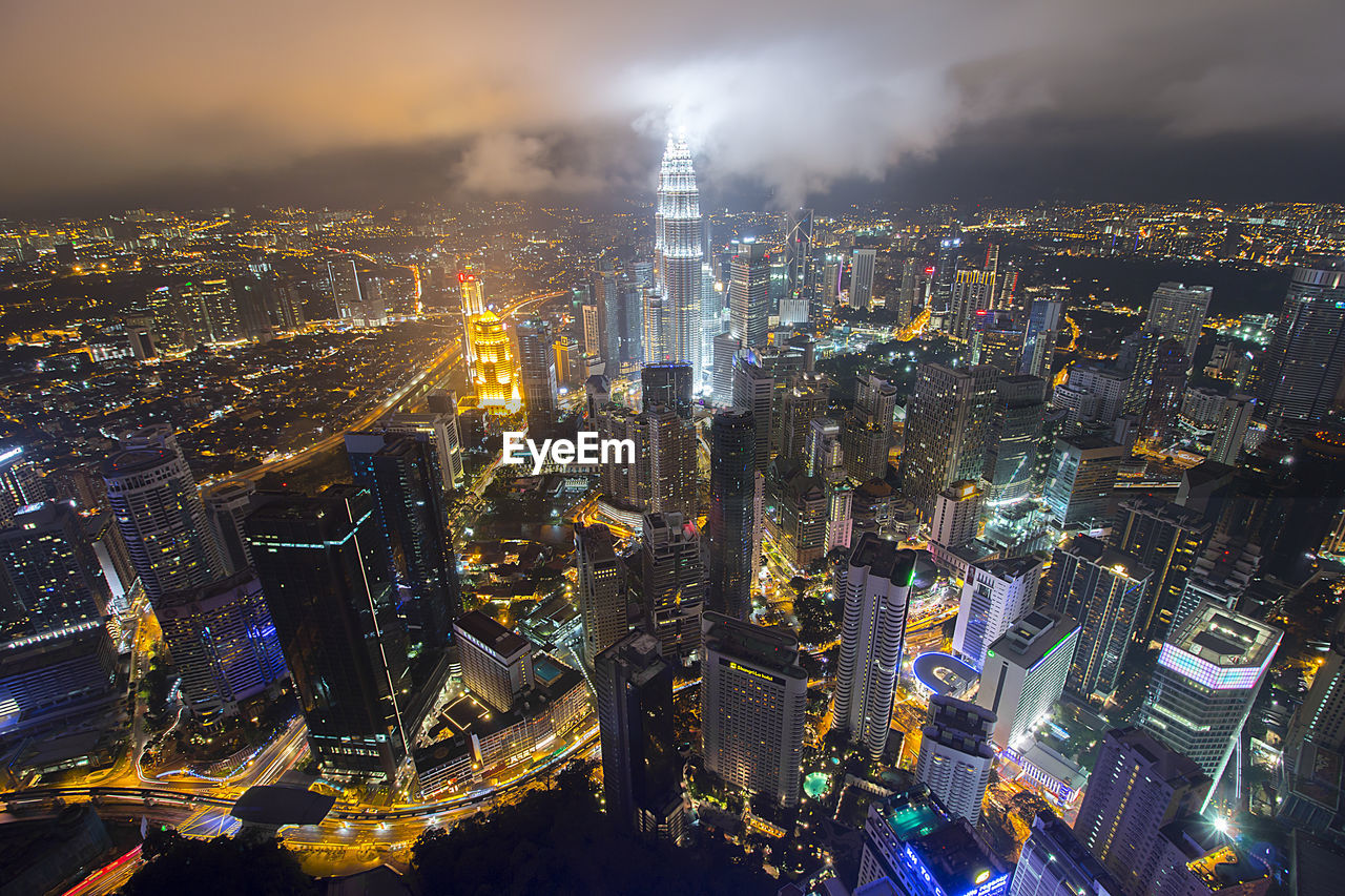 Petronas towers amidst illuminated cityscape against sky at night