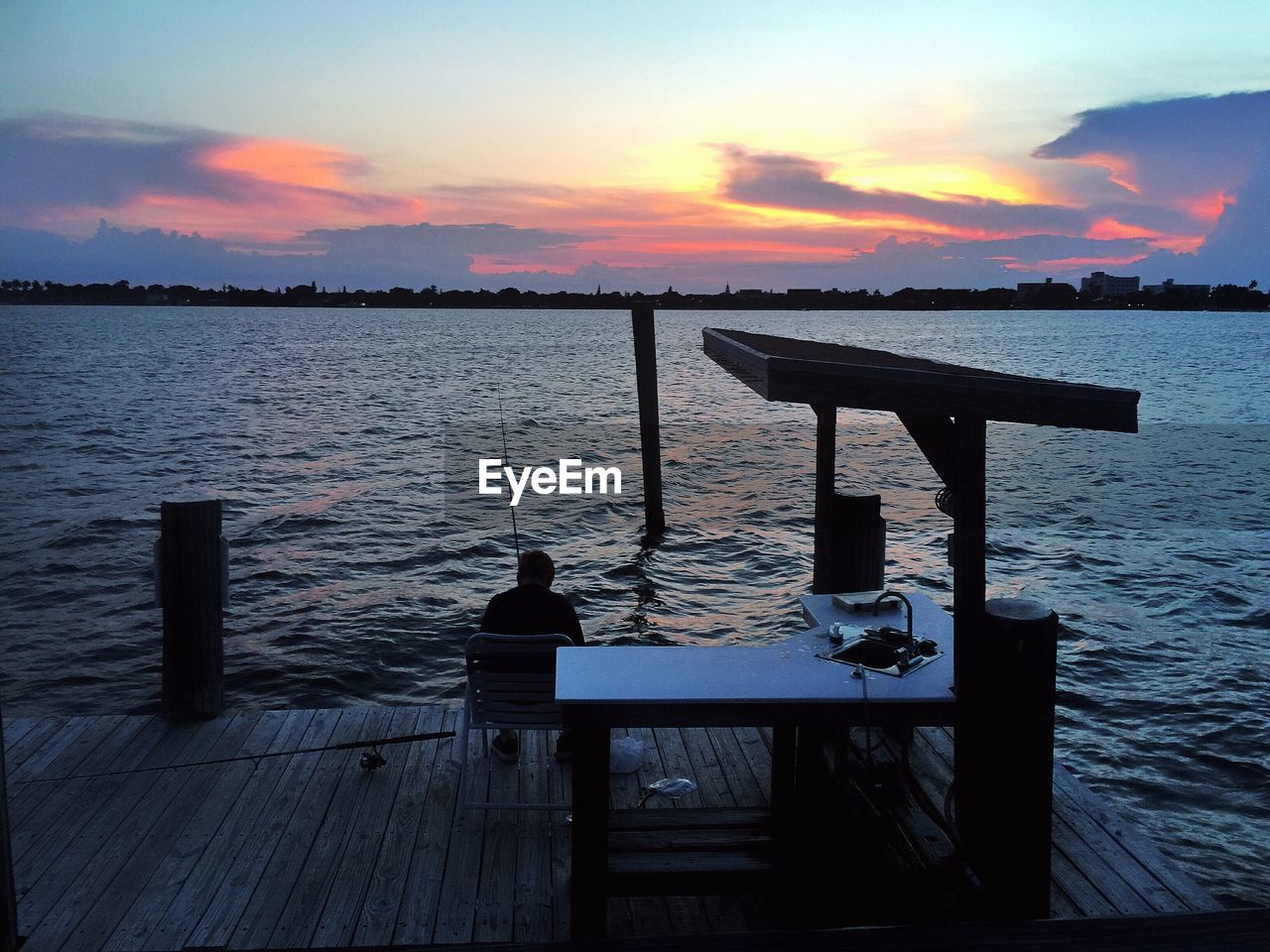 Pier on lake at sunset