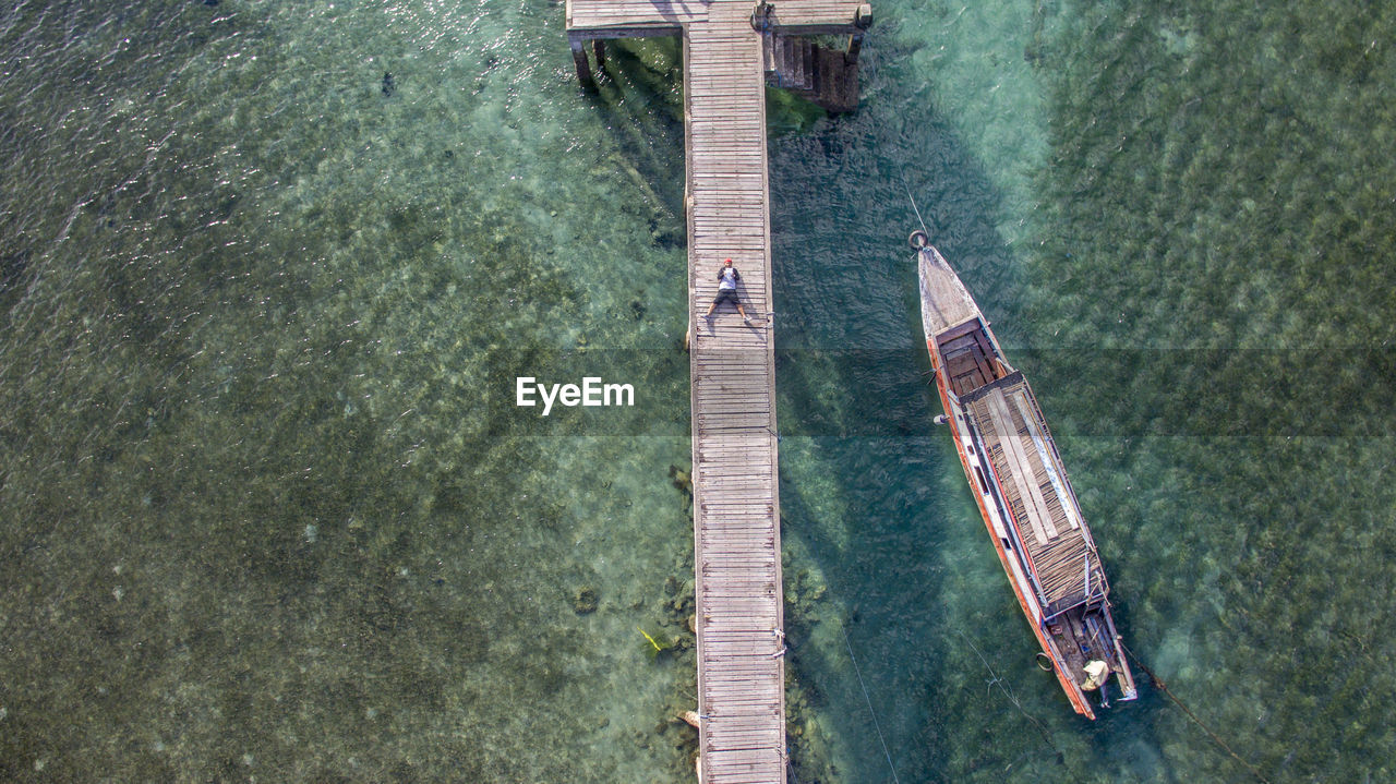 Aerial view of man lying on pier in sea