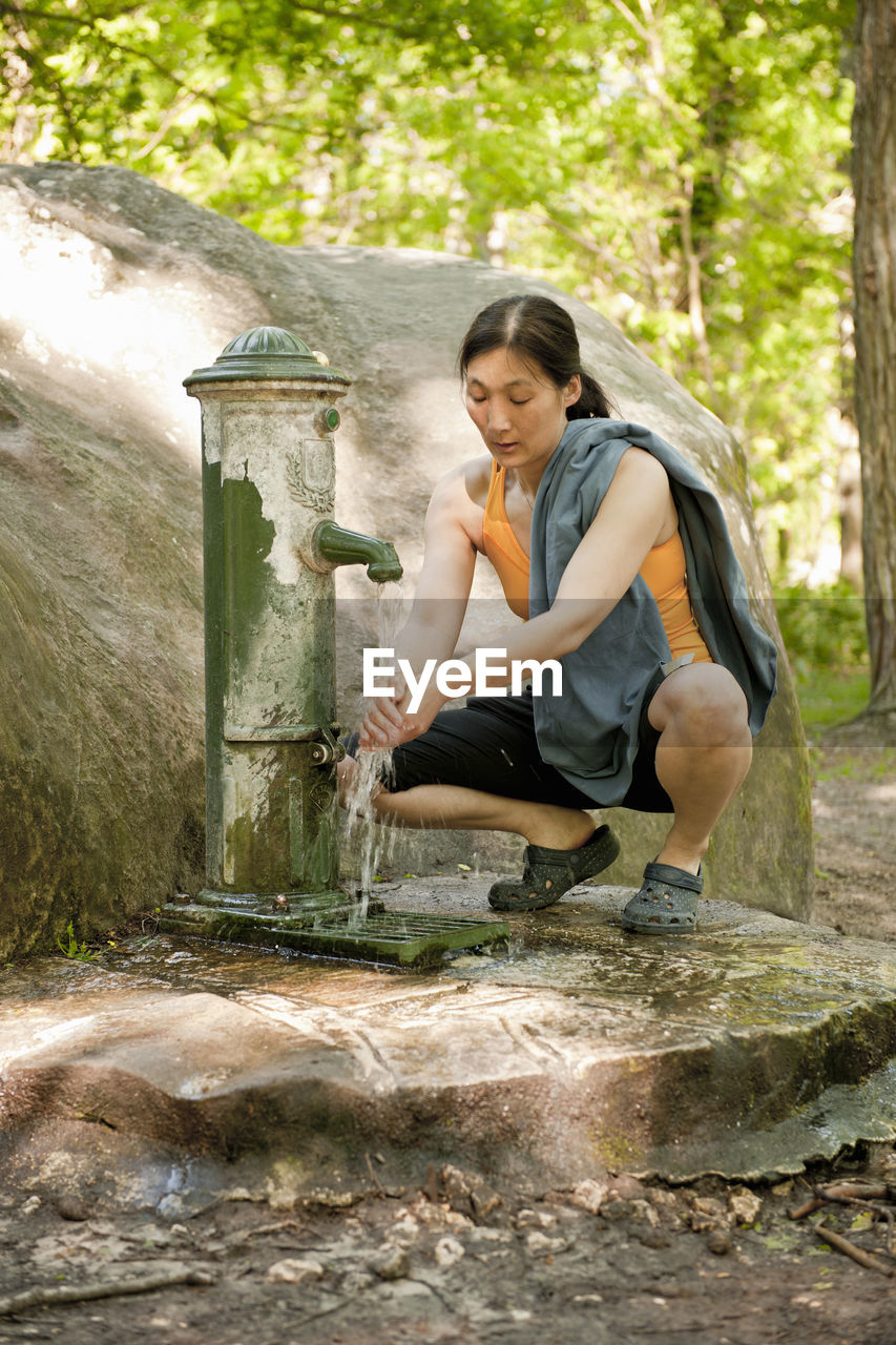 Woman washing her hands at water pump in fontainebleau forest