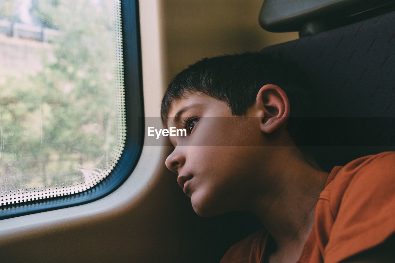 Close-up of thoughtful boy looking away while traveling in train