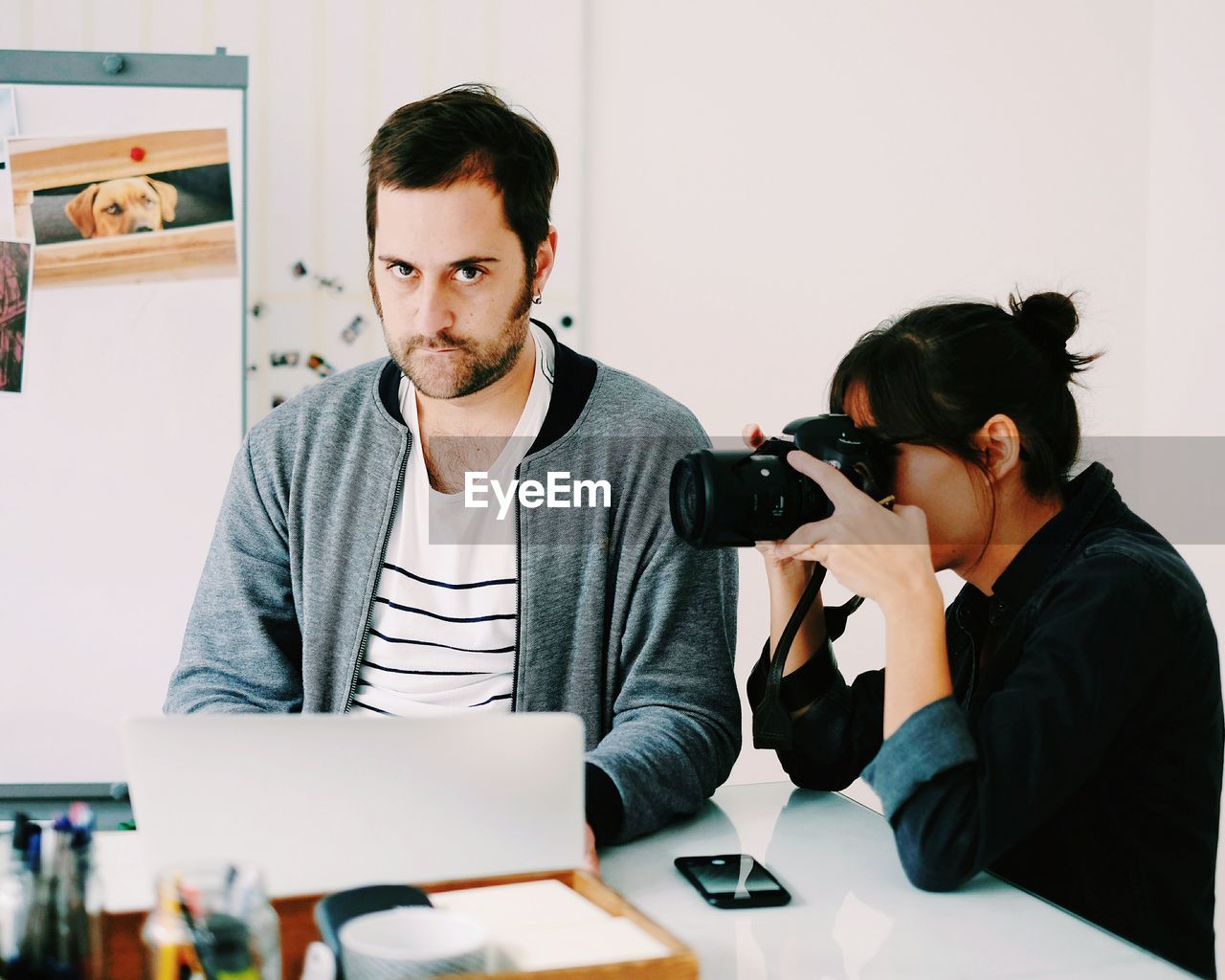 FRIENDS LOOKING AT CAMERA WHILE SITTING ON TABLE