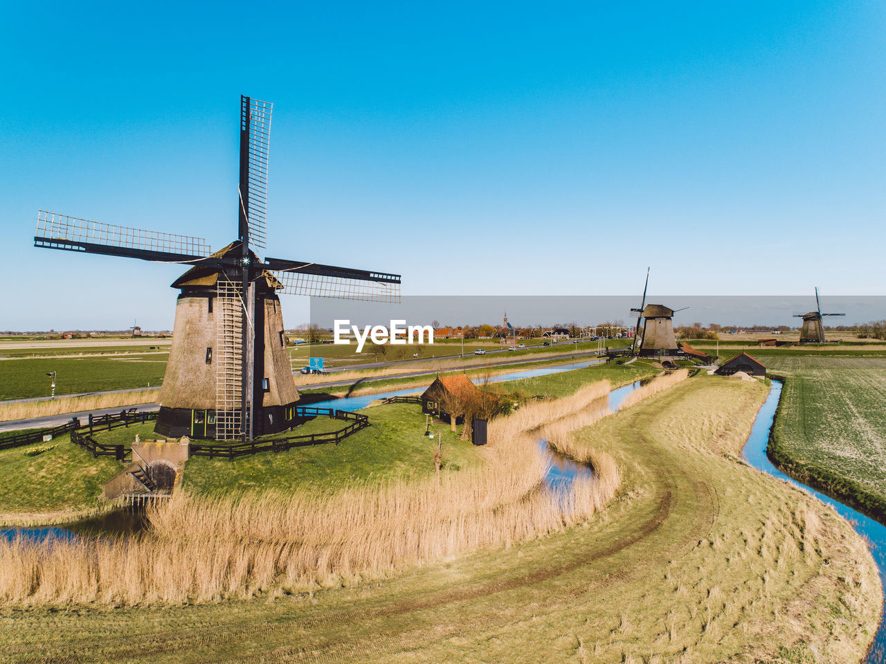 Traditional windmill on field against clear blue sky