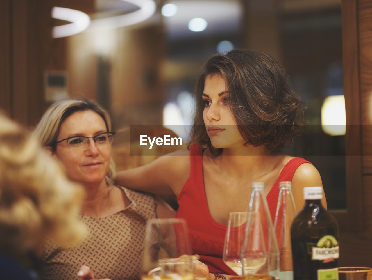 Mother and daughter looking away while sitting at restaurant