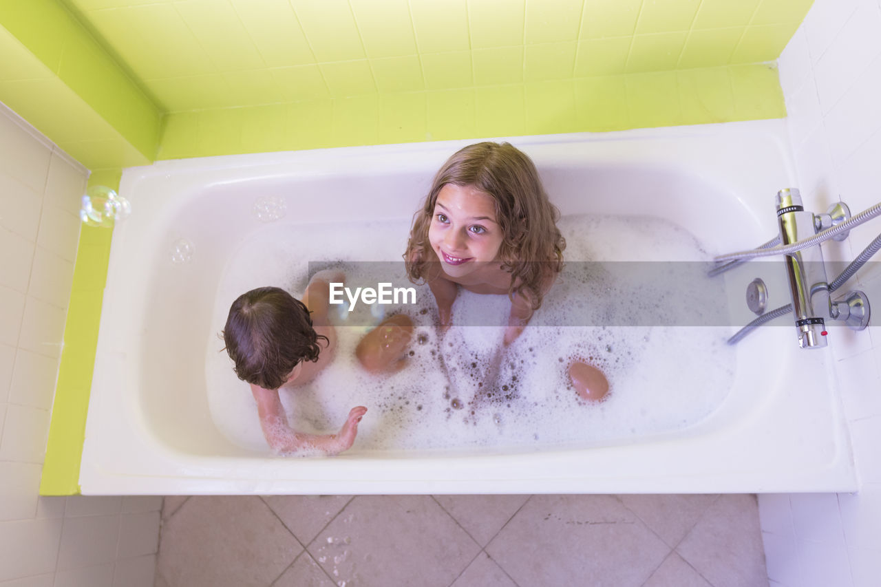 High angle view of happy siblings playing in bathtub