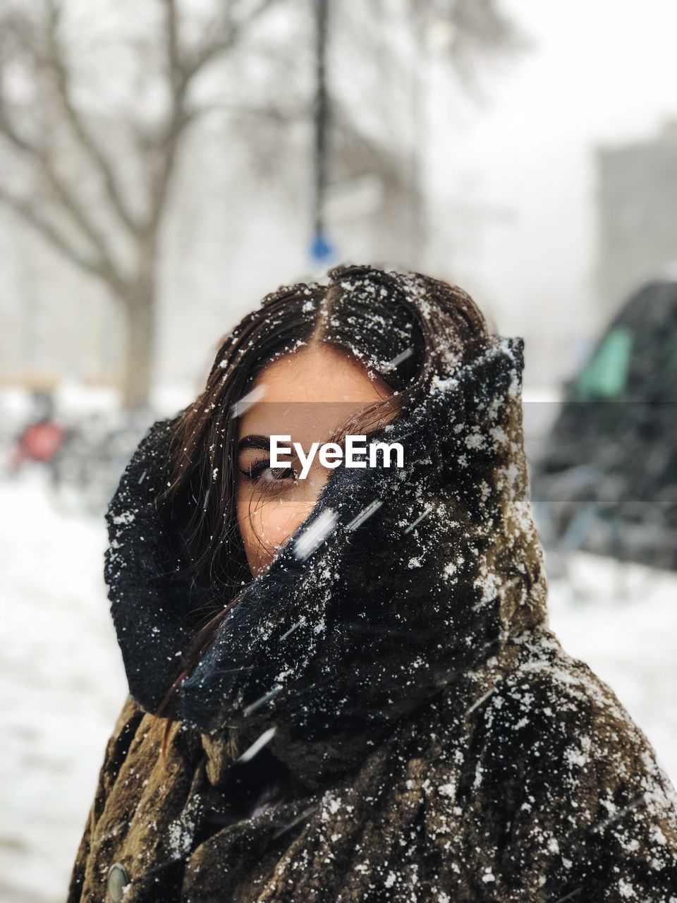 Close-up of young woman with snow during winter