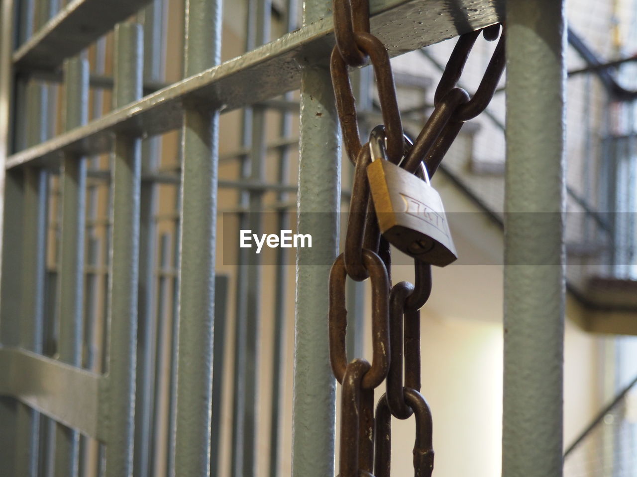 Close-up of lock attached to chain hanging on prison bars