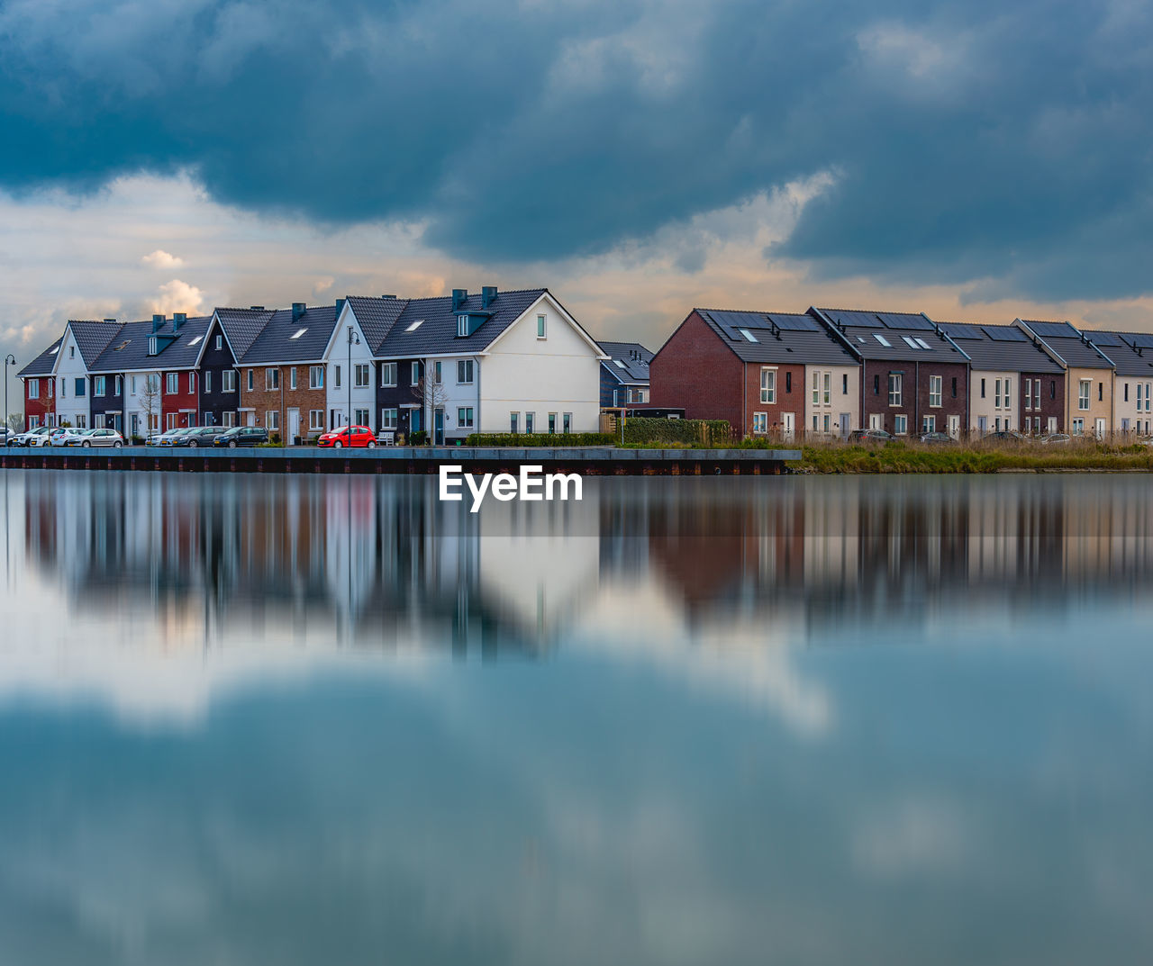 Houses by lake against cloudy sky in city
