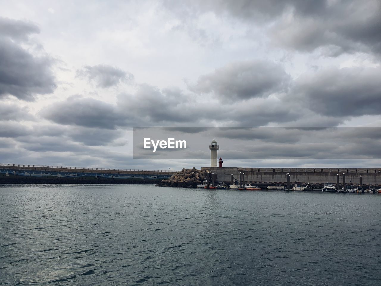 View of building by sea against cloudy sky