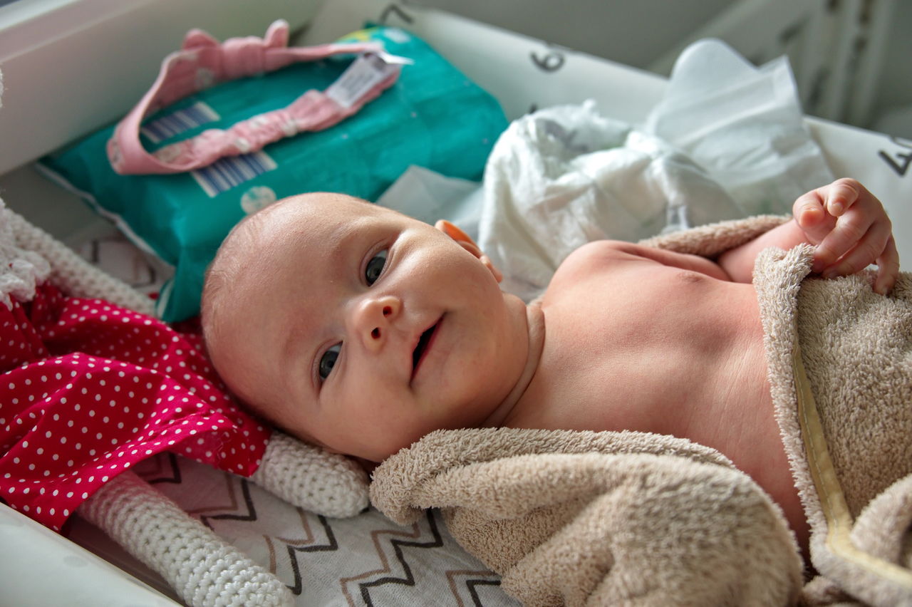 Newborn baby girl in towel after bath ready for putting clothes