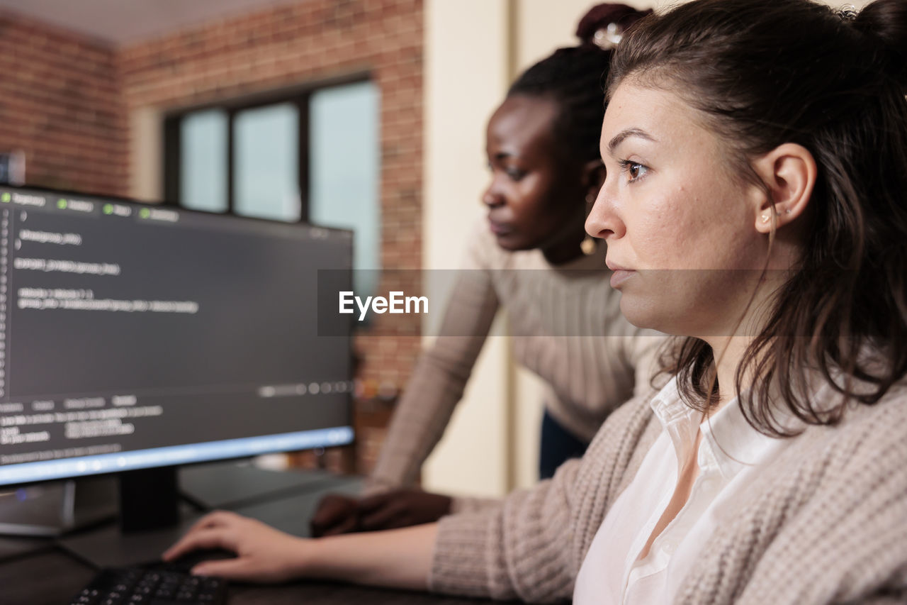 side view of young woman using laptop at office