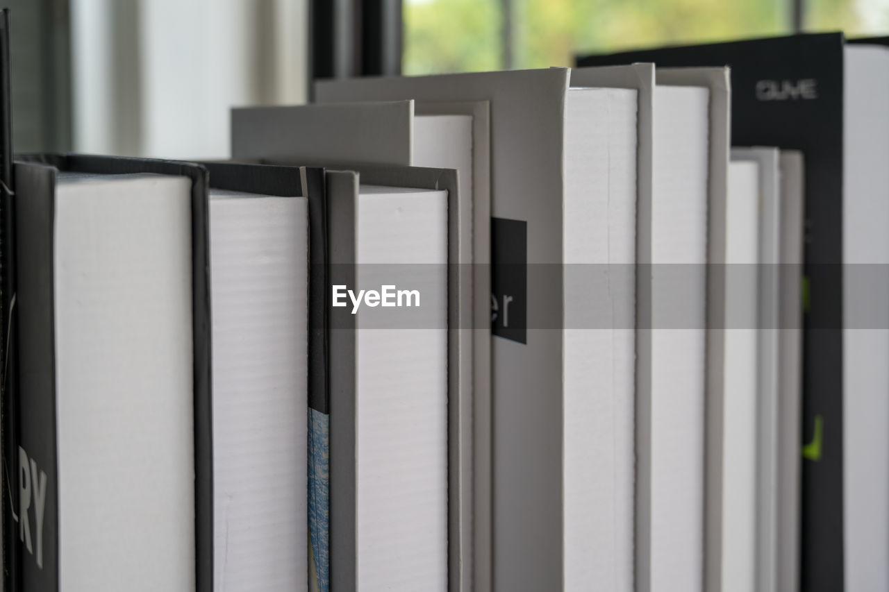 Hardcover books back edges on wooden shelves display of retail book store or shop over close up