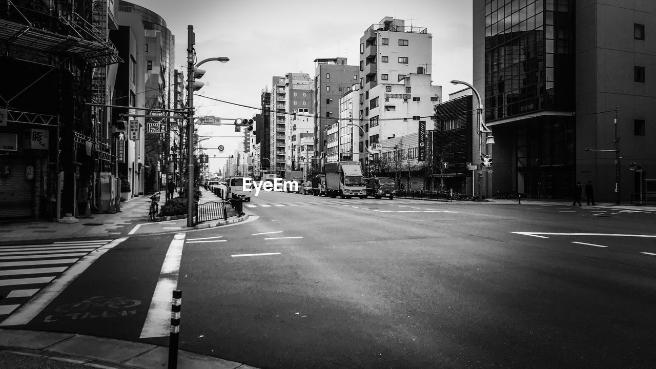 MAN WALKING ON ROAD ALONG BUILDINGS