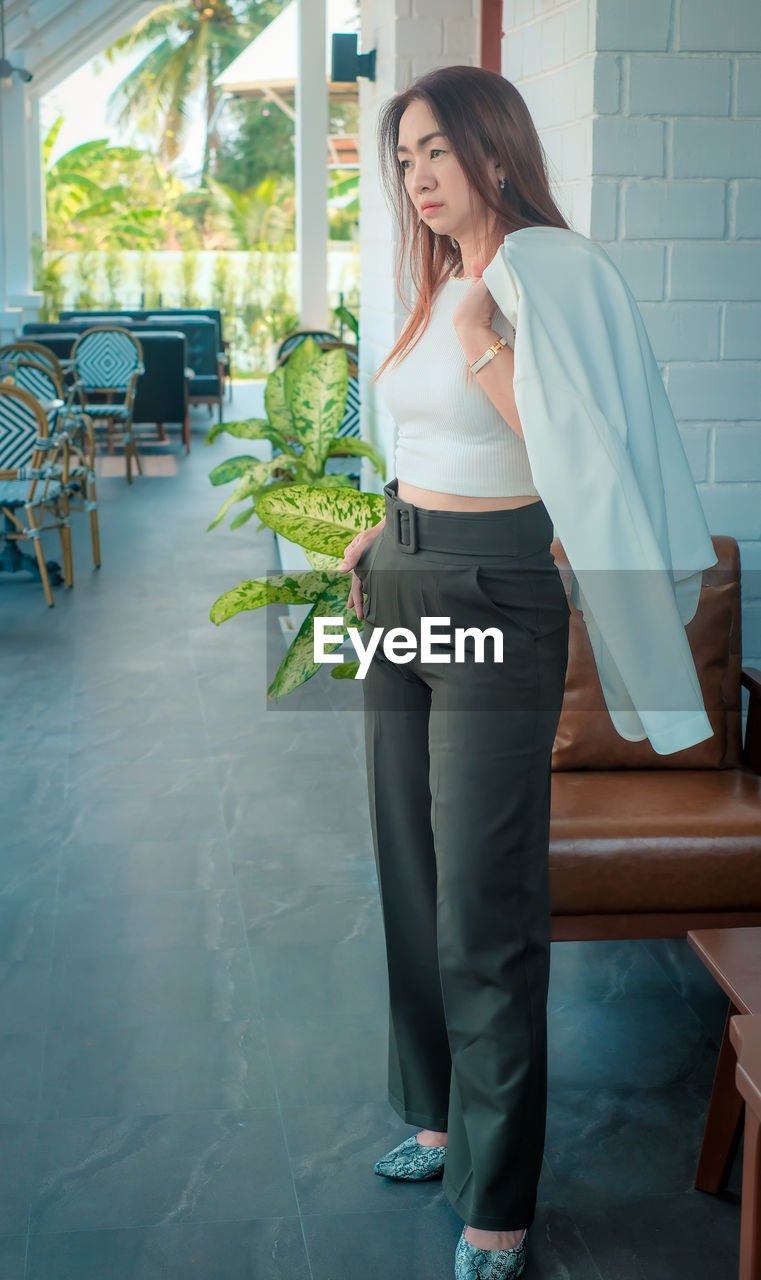 Full length of woman standing by potted plant