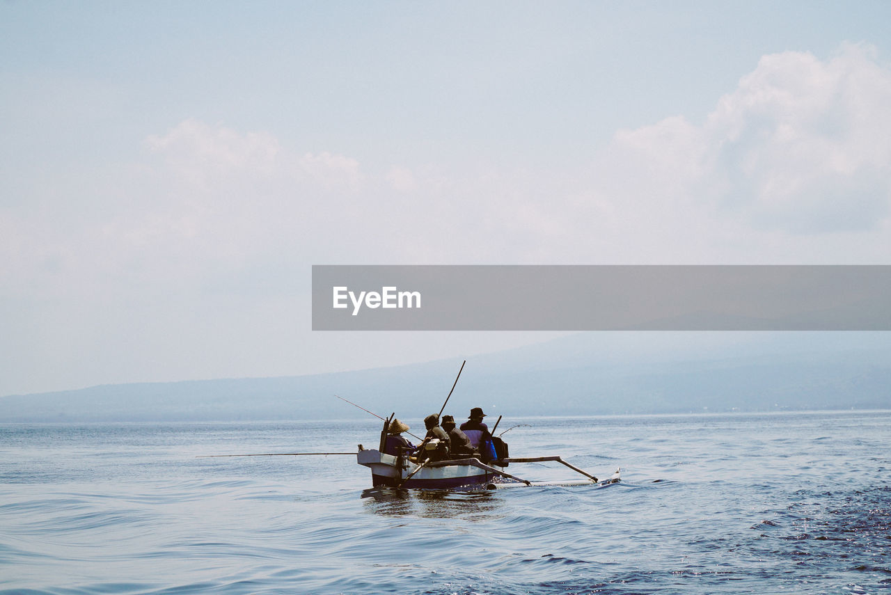 People in boat on sea against sky