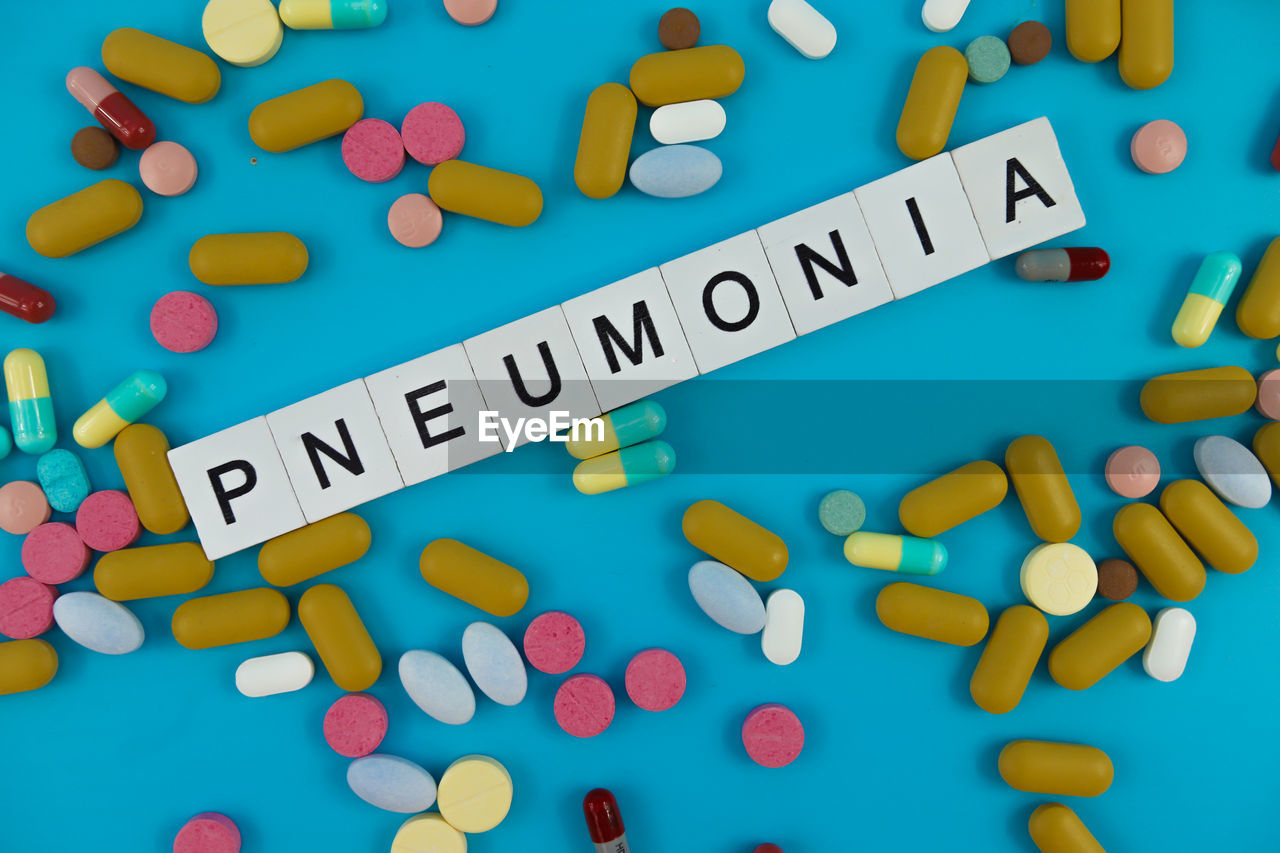 The word of pneumonia with pill on blue background