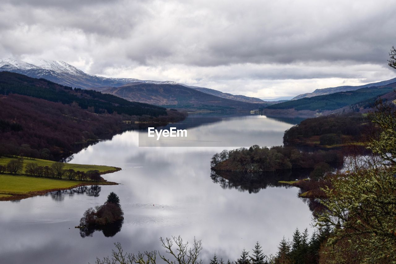 Scenic view of mountains and lake against cloudy sky