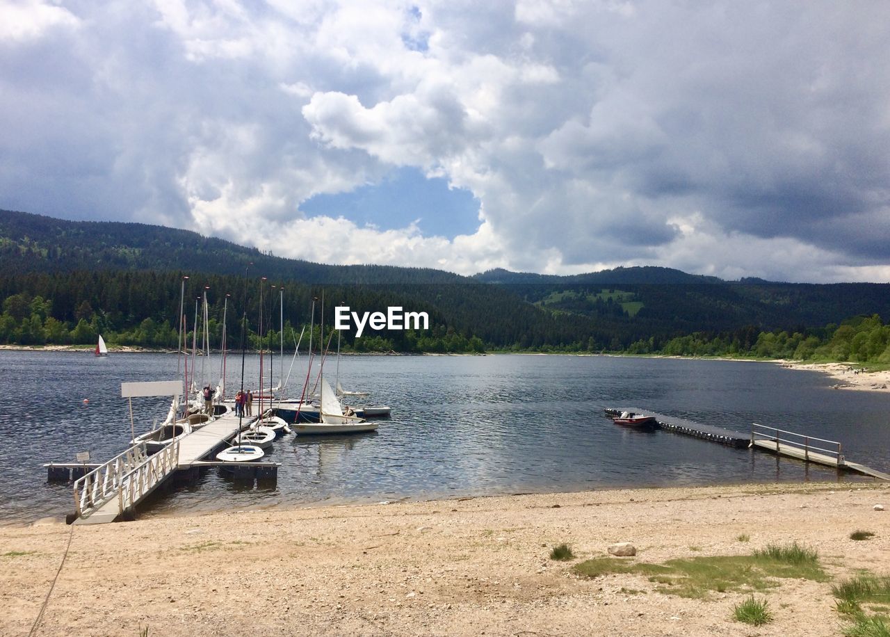 Sailboats moored on lake against sky