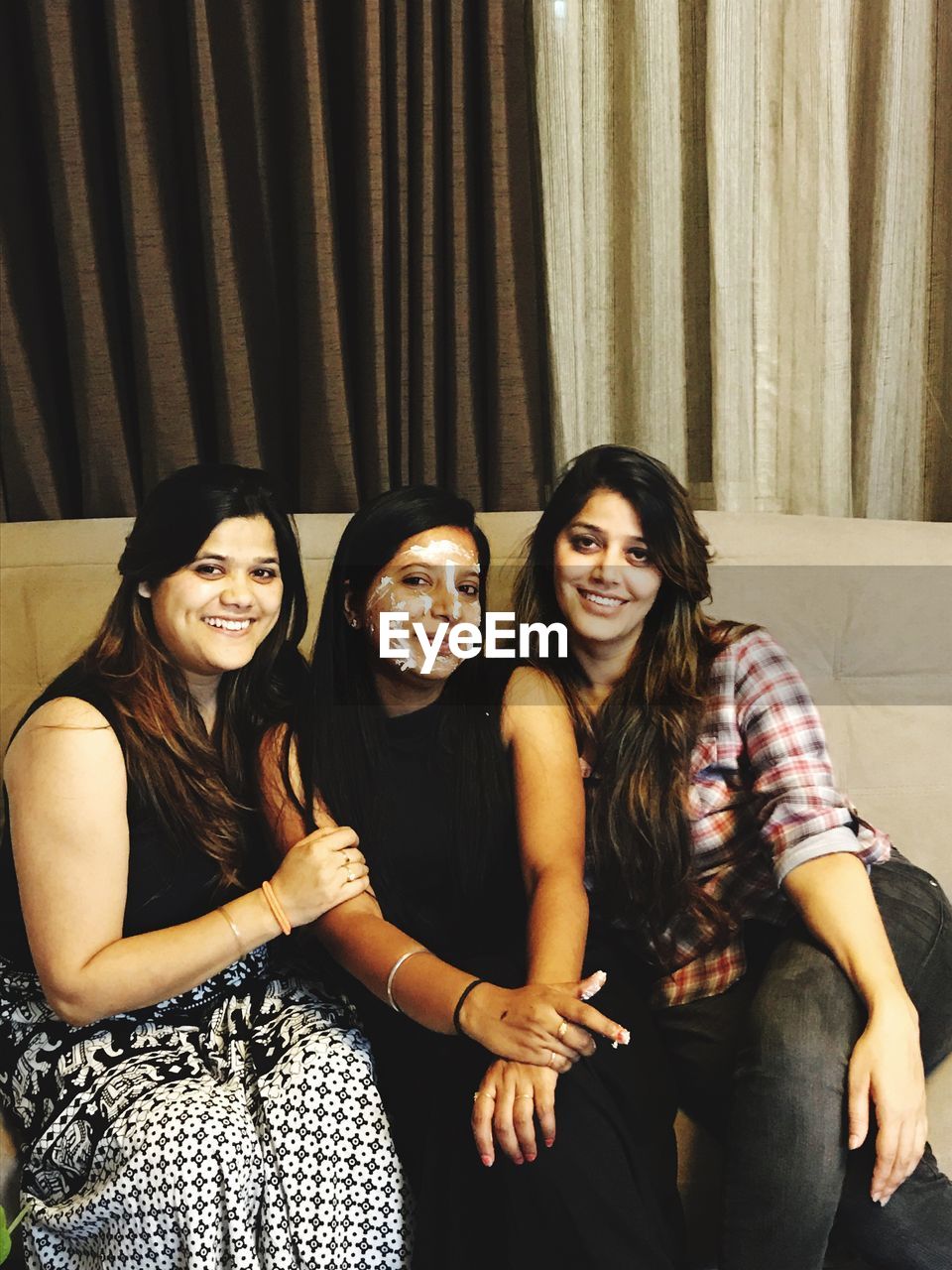 Portrait of female friends sitting on sofa at home