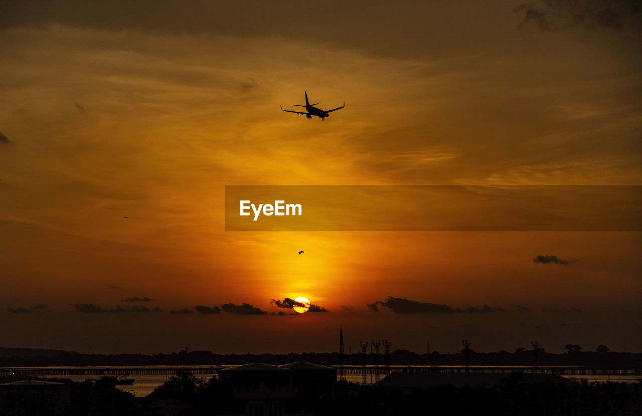 Low angle view of silhouette airplane against sky during sunset