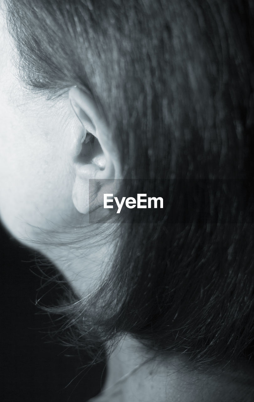 Close-up of woman with hearing aid against black background