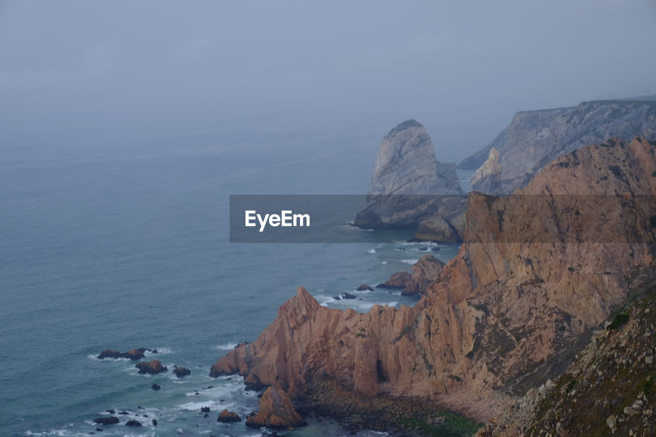 Rock formations by sea against sky