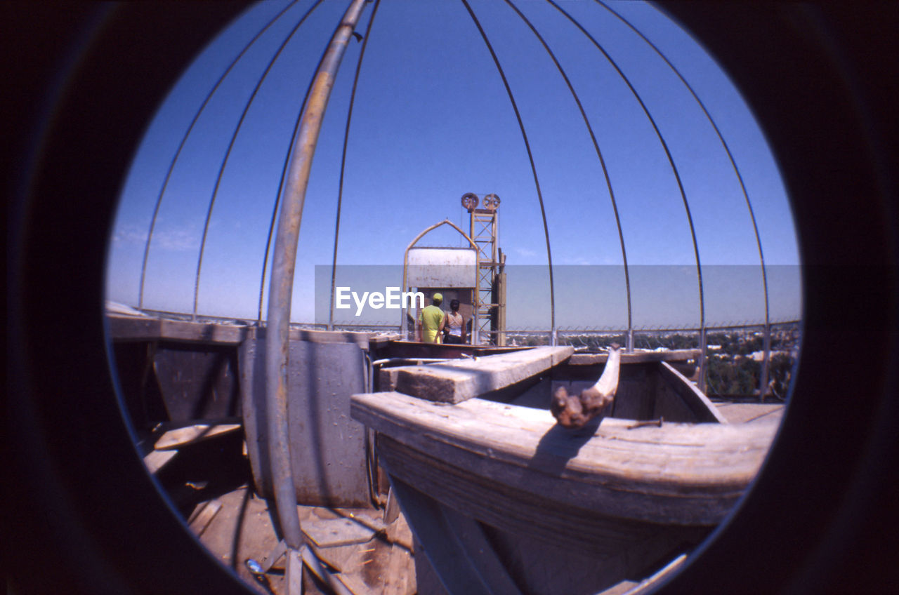 Couple at observation point against blue sky seen through glass