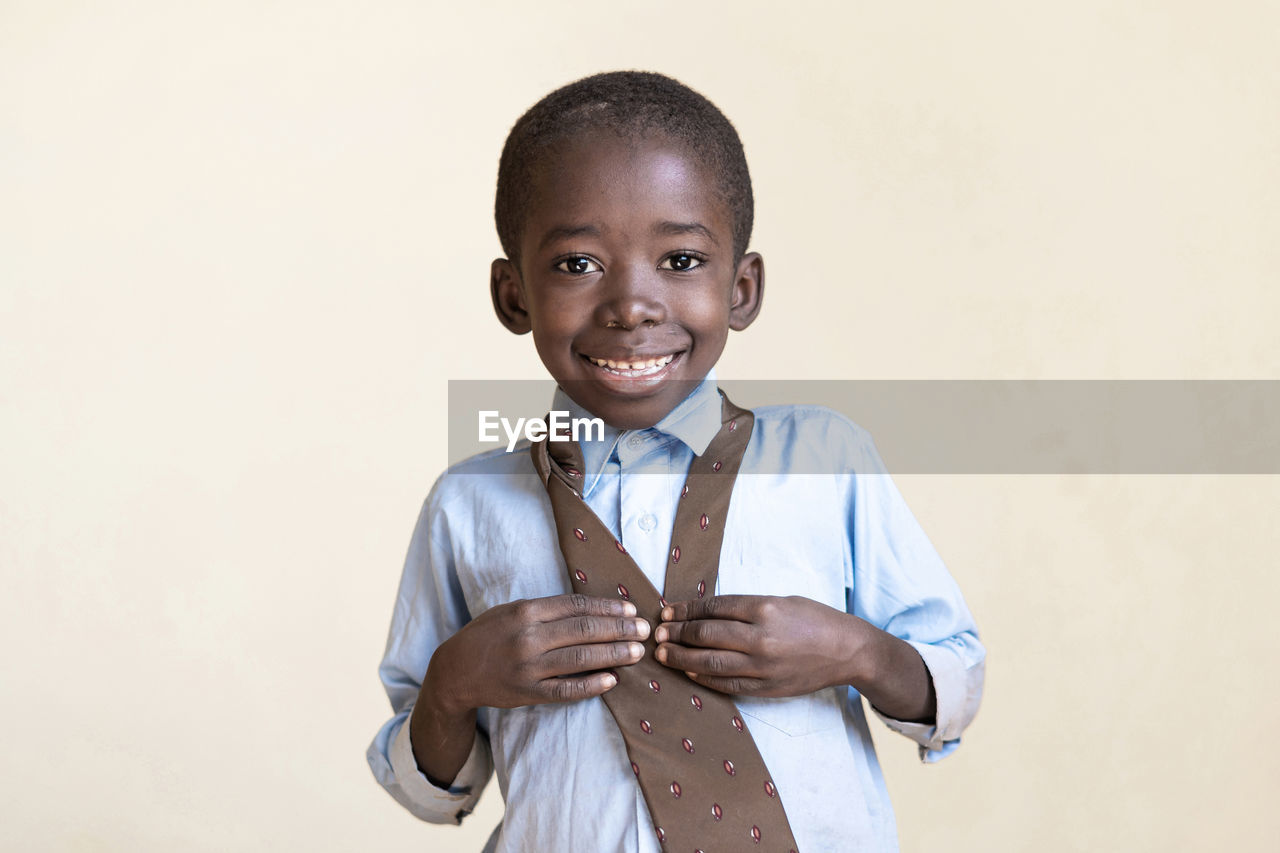 Portrait of smiling boy standing against white background