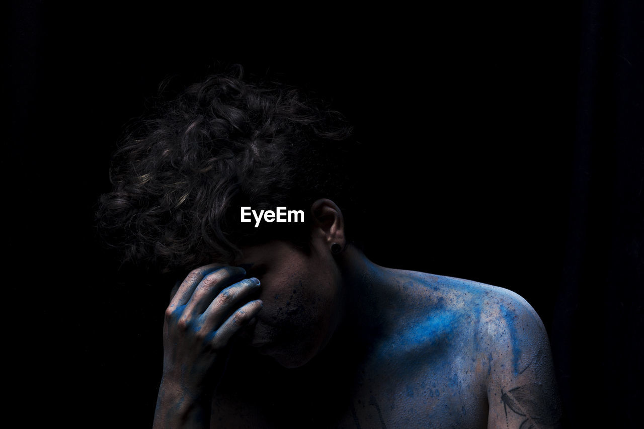 Close-up of man covered with powder paint against black background