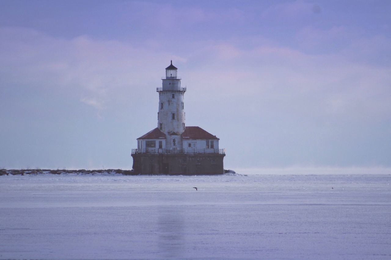 Lighthouse by sea against sky