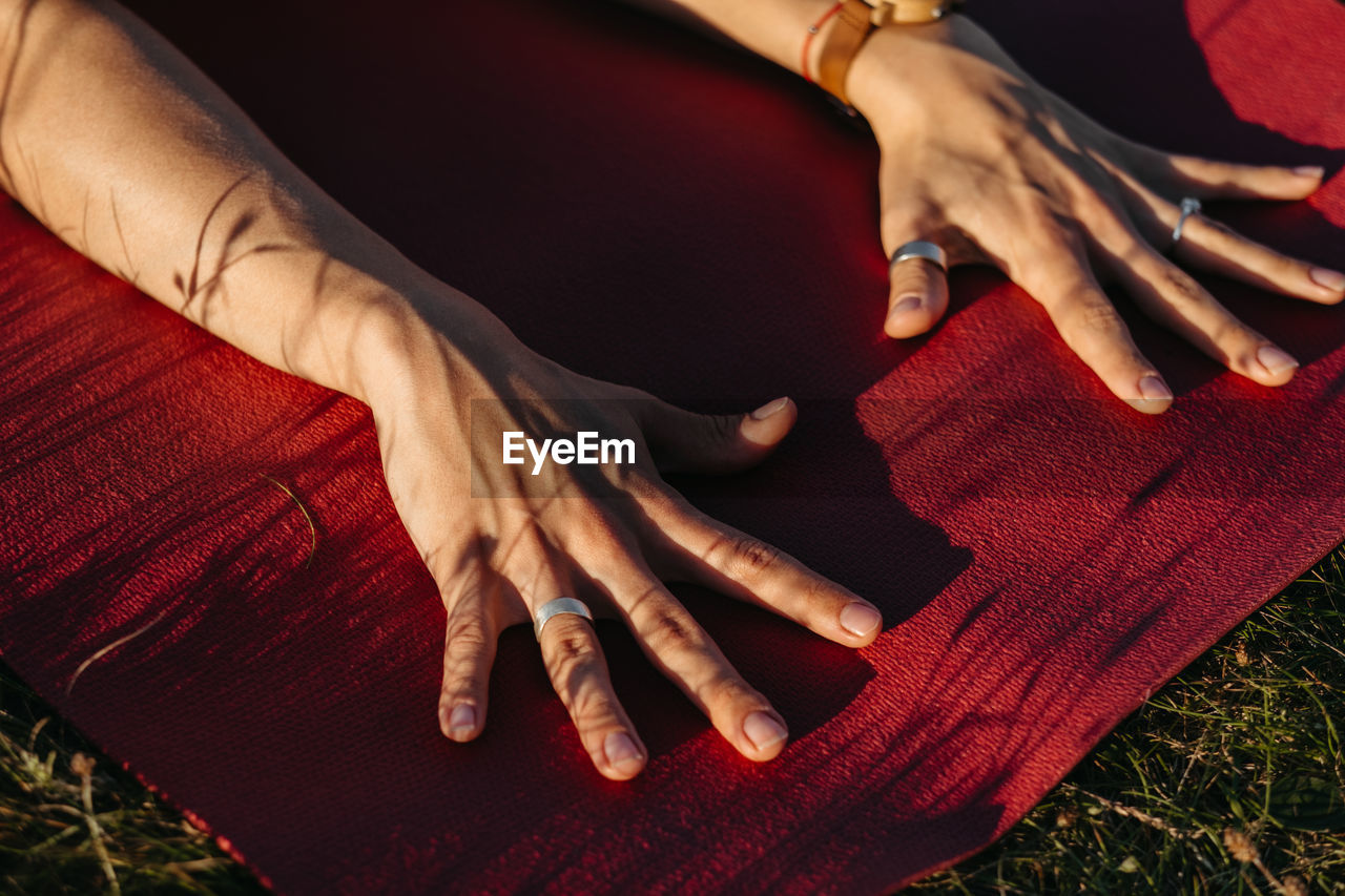 Close up unrecognisable woman holding her hands on the mat during yoga outdoors at sunset	
