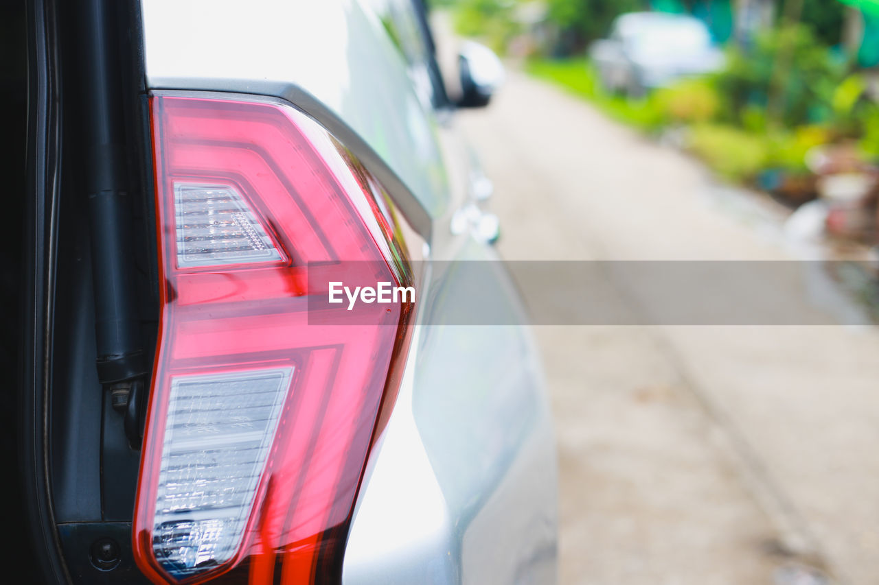 car, mode of transportation, transportation, motor vehicle, vehicle, land vehicle, wheel, city car, driving, travel, automotive exterior, day, city, automotive tail & brake light, focus on foreground, auto part, outdoors, street, road, red, close-up, communication