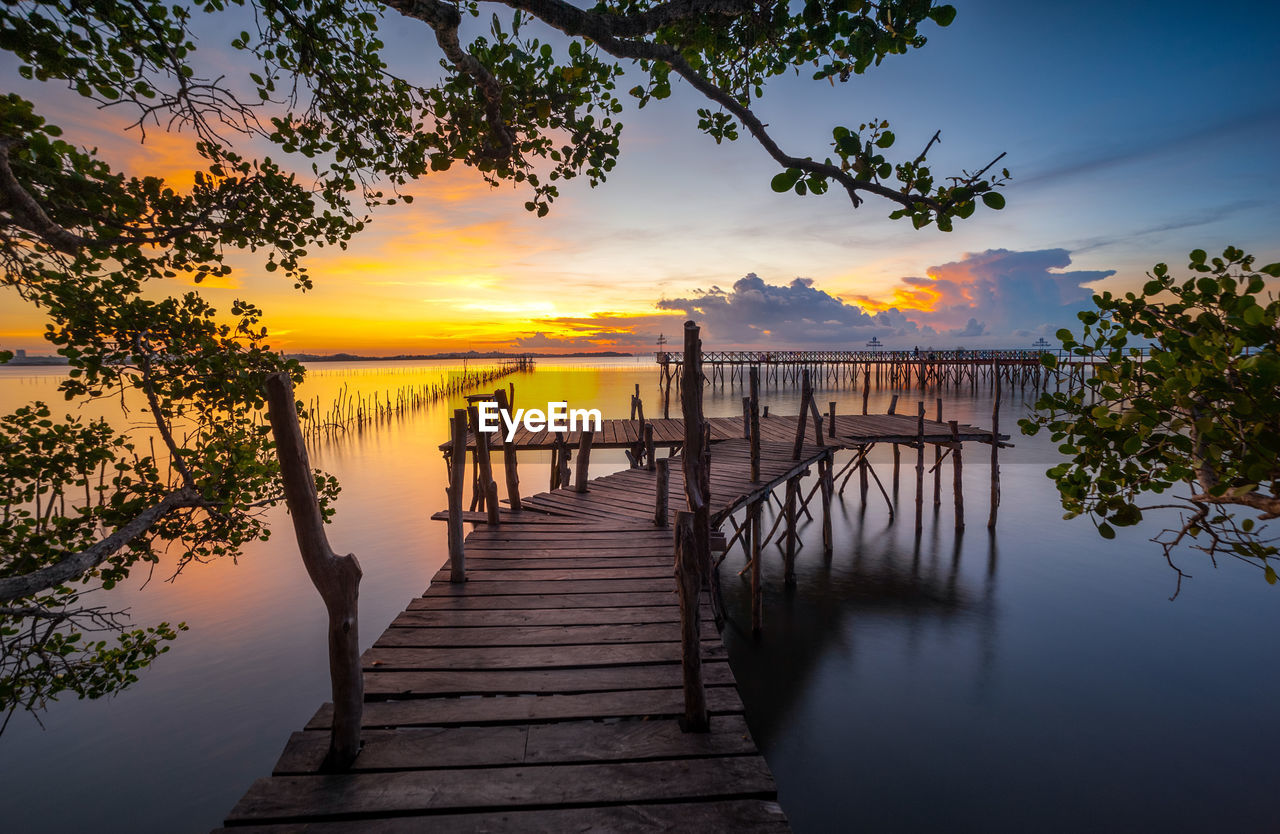 Pier over lake against sky during sunset