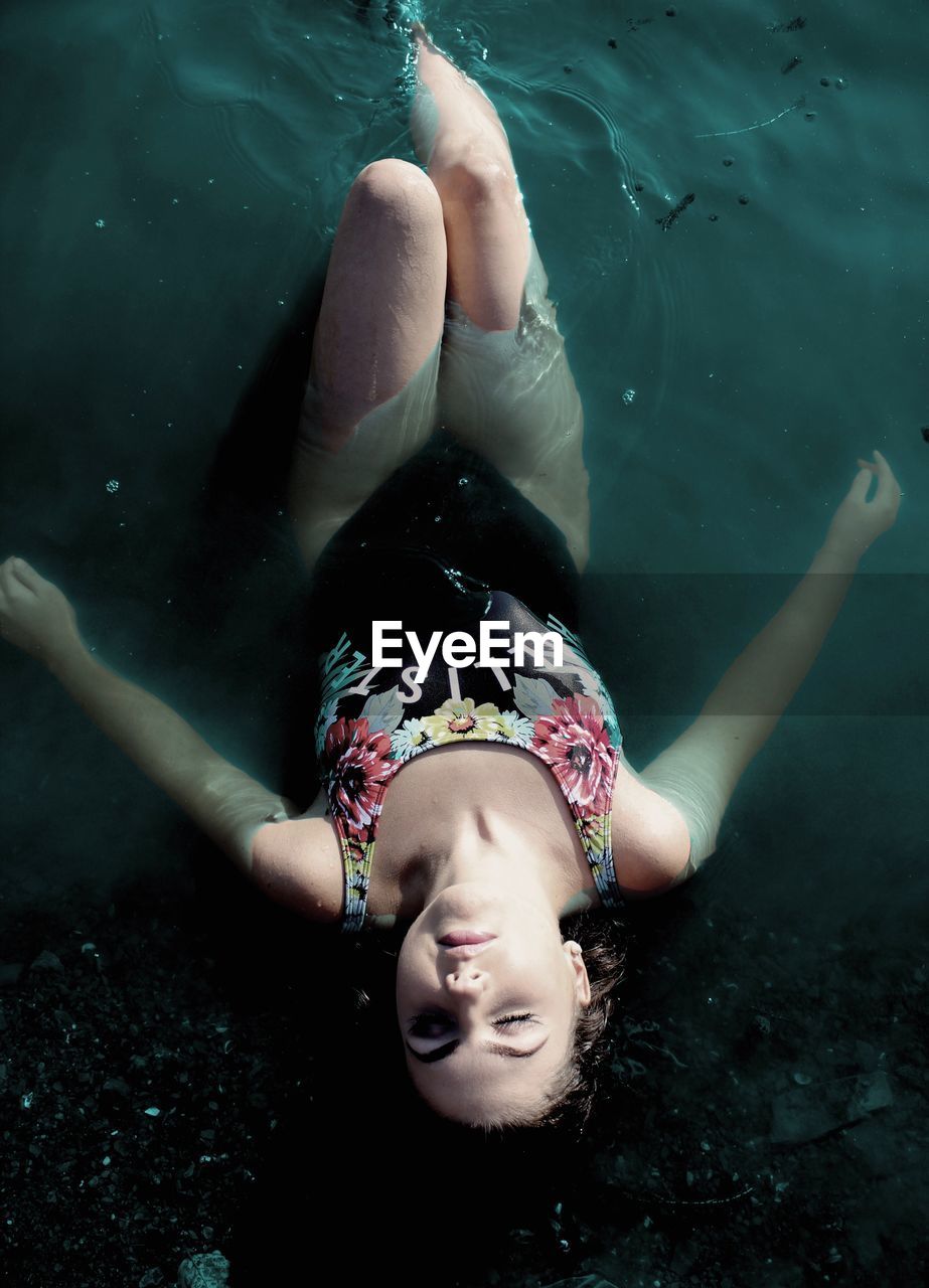 High angle view of young woman lying in lake