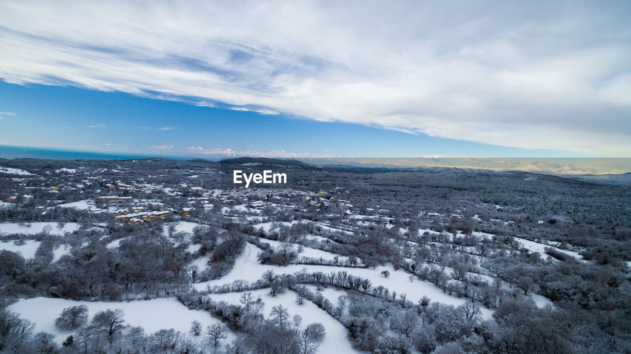 AERIAL VIEW OF SNOW COVERED LANDSCAPE AGAINST SKY