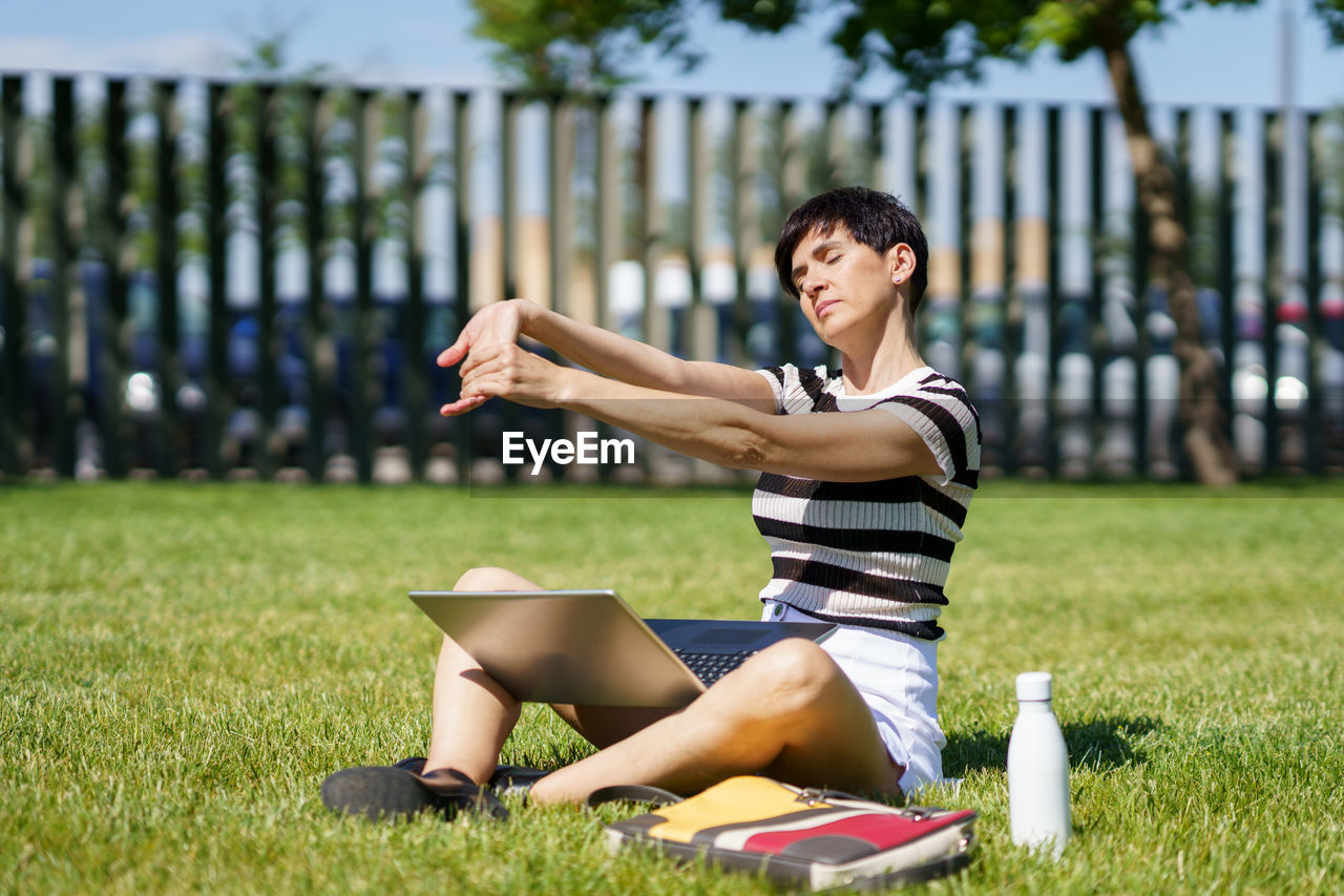 side view of young woman sitting on field