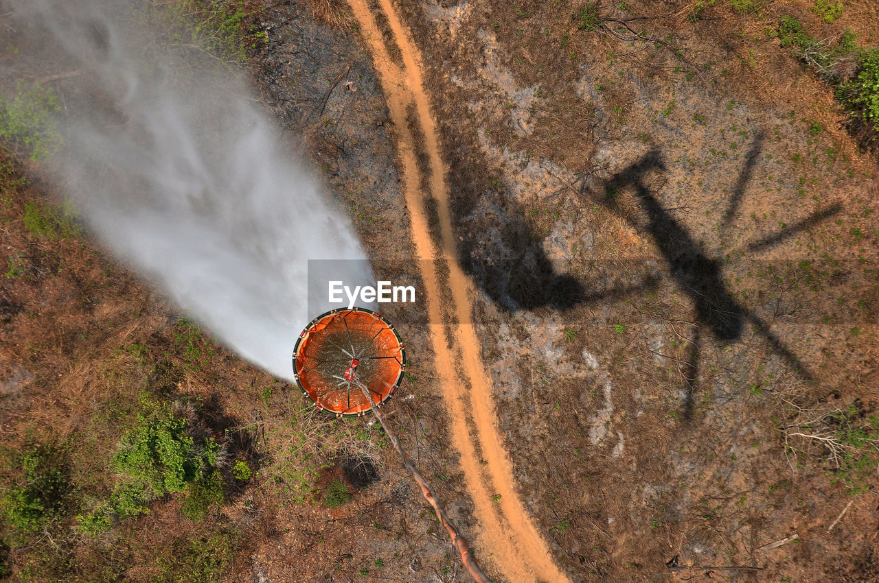 High angle view of helicopter pulling container over landscape