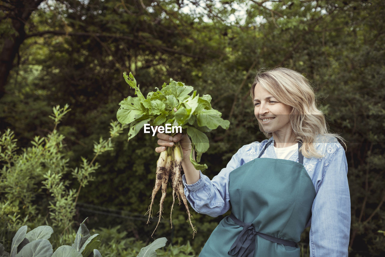 Young woman smiling while holding plants