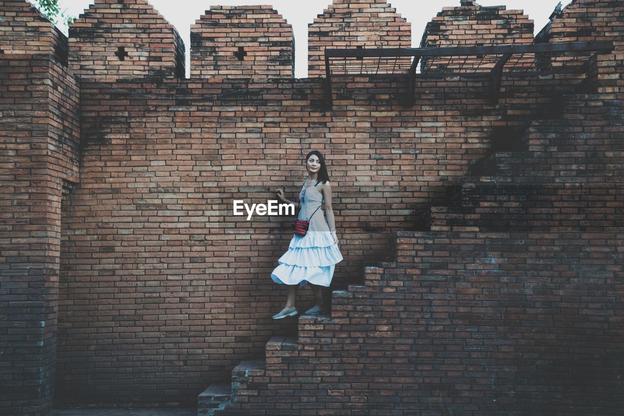 Woman walking on steps by brick wall