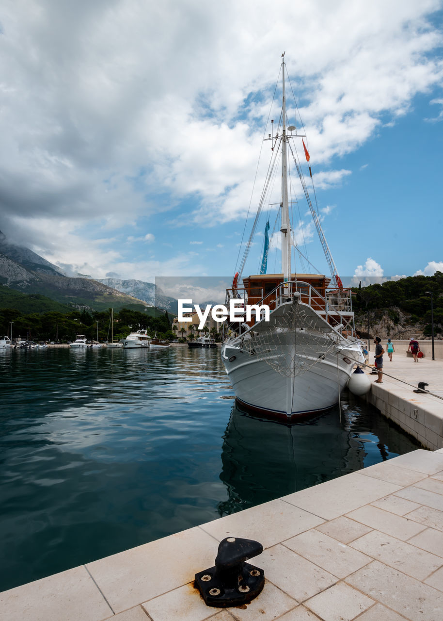 SAILBOATS MOORED ON HARBOR BY SEA AGAINST SKY