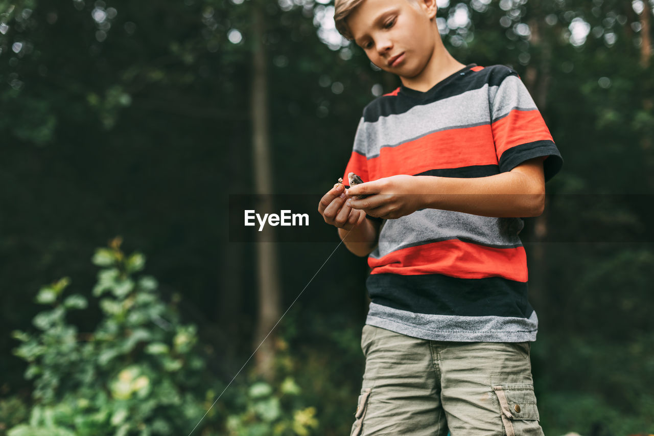 A teenage boy takes a newly caught fish off the hook. the first catch, hobbies, recreation