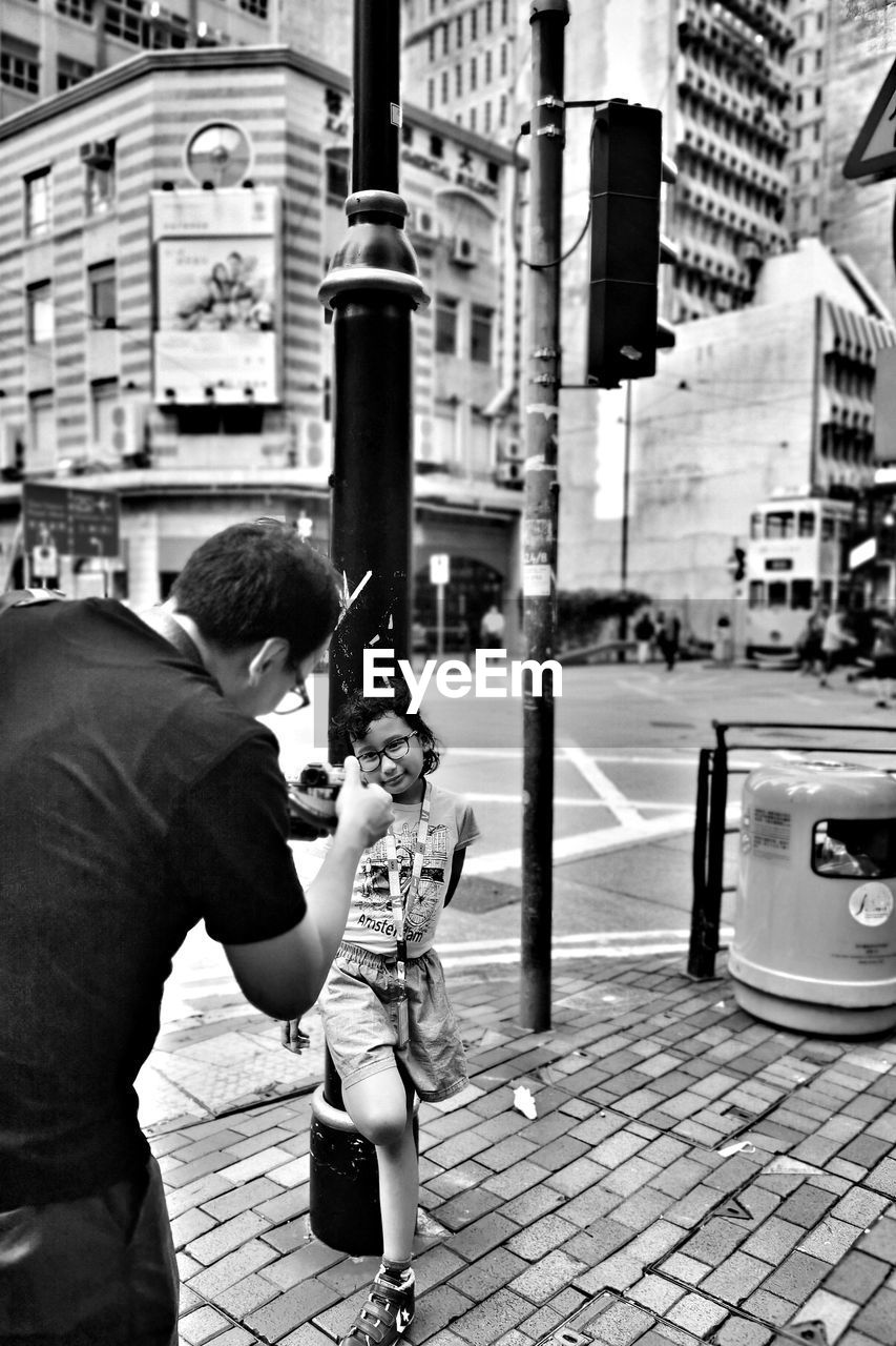 Man photographing woman by street