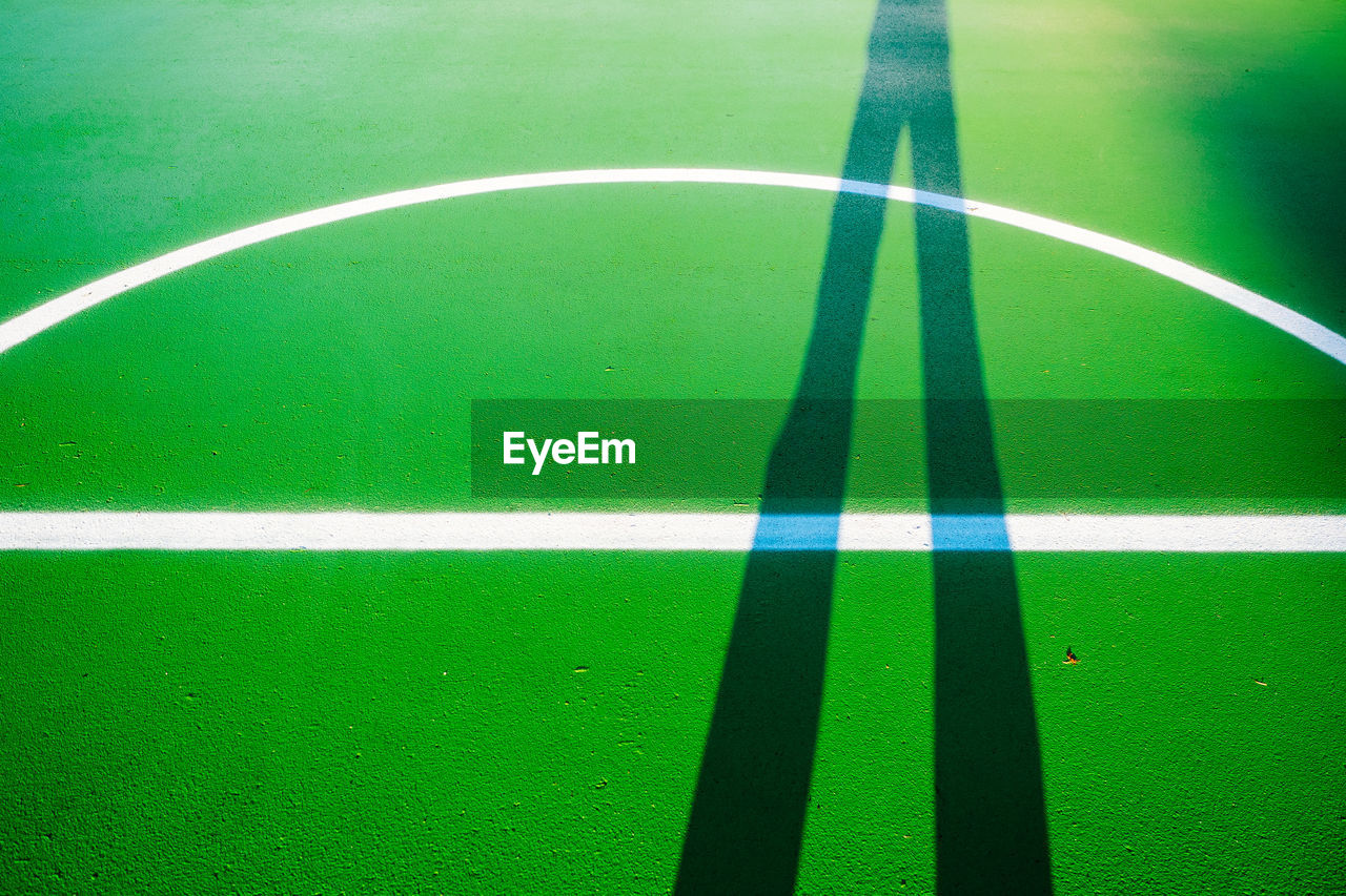 Shadow of person standing on green basketball court