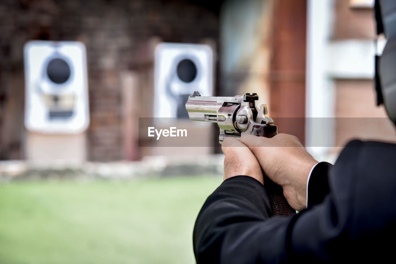 Midsection of man aiming gun during target shooting