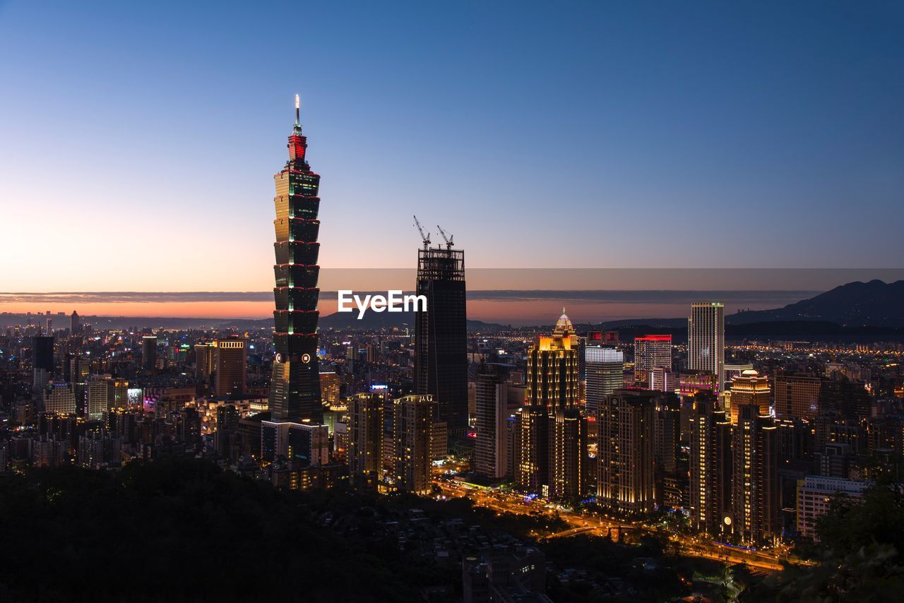 Illuminated cityscape against sky at night